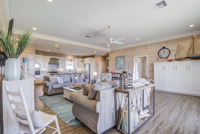 living room with light wood-style floors, recessed lighting, visible vents, and crown molding