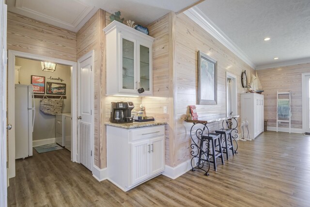 kitchen with light stone countertops, separate washer and dryer, white cabinetry, light hardwood / wood-style floors, and white fridge