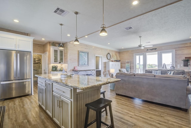 kitchen featuring white cabinets, glass insert cabinets, open floor plan, a center island, and freestanding refrigerator