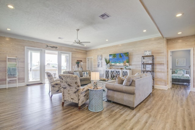 living area with ornamental molding, visible vents, light wood-style flooring, and a textured ceiling