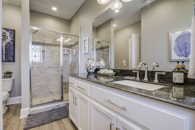 full bathroom featuring toilet, a stall shower, wood finished floors, and vanity