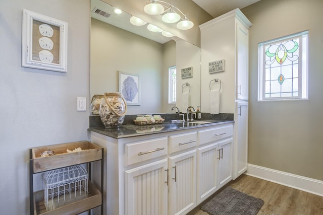 bathroom featuring visible vents, vanity, baseboards, and wood finished floors