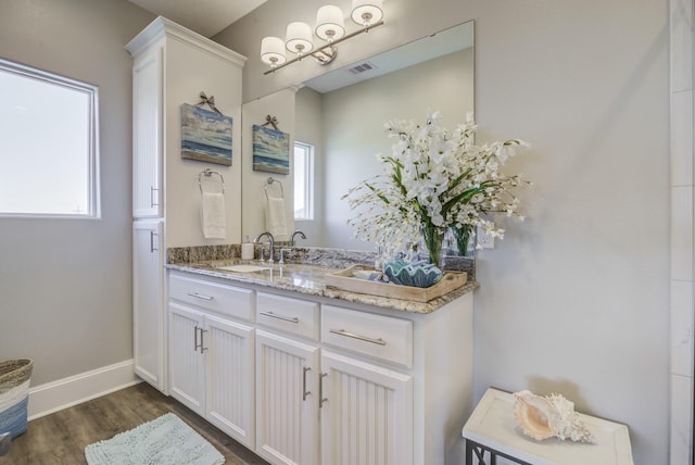 bathroom featuring baseboards, visible vents, wood finished floors, and vanity