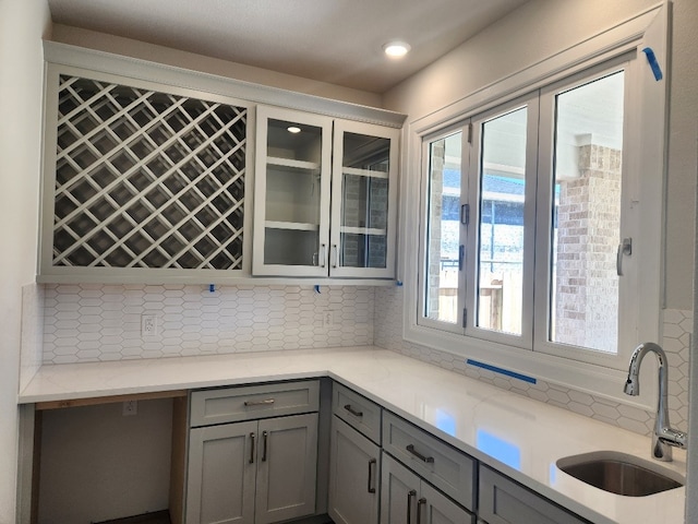 kitchen with gray cabinetry, decorative backsplash, and sink