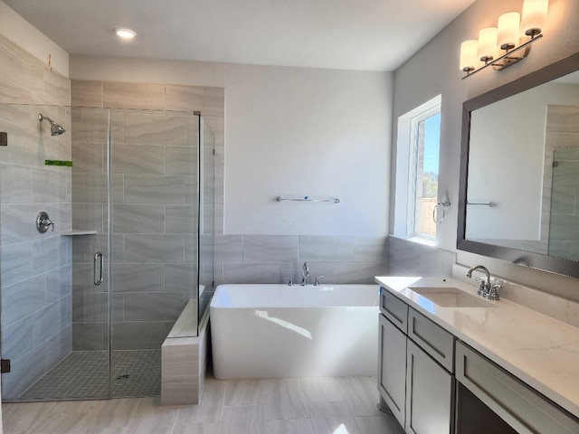 bathroom featuring plus walk in shower, vanity, and tile walls