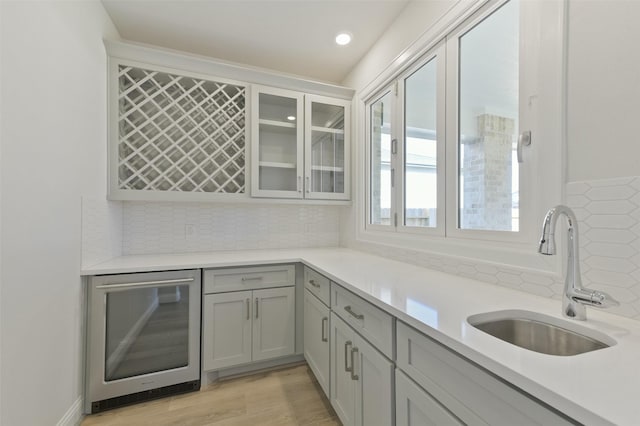 kitchen with wine cooler, sink, backsplash, and gray cabinets