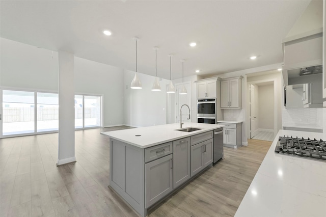 kitchen featuring sink, hanging light fixtures, appliances with stainless steel finishes, gray cabinets, and backsplash