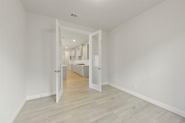 spare room with light hardwood / wood-style floors and french doors