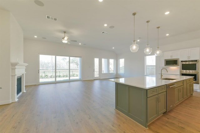 9931 Hunters Run Dr, Missouri City, TX 77459 - kitchen featuring appliances with stainless steel finishes, sink, a kitchen island with sink, and light hardwood / wood-style flooring
