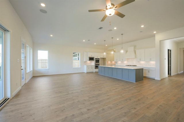 9931 Hunters Run Dr, Missouri City, TX 77459 - kitchen featuring appliances with stainless steel finishes, white cabinets, hanging light fixtures, custom exhaust hood, and a center island with sink