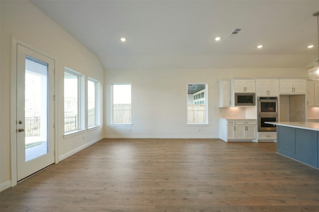 9931 Hunters Run Dr, Missouri City, TX 77459 - kitchen with appliances with stainless steel finishes, pendant lighting, white cabinetry, lofted ceiling, and light hardwood / wood-style floors