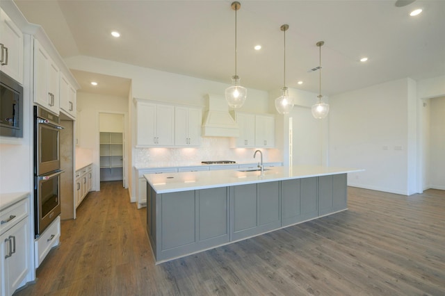 9931 Hunters Run Dr, Missouri City, TX 77459 - kitchen with premium range hood, white cabinetry, a kitchen island with sink, and hanging light fixtures