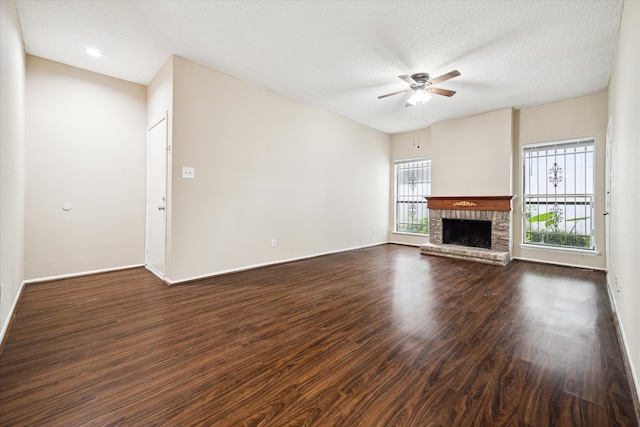 unfurnished living room featuring a textured ceiling, a brick fireplace, ceiling fan, and dark hardwood / wood-style floors