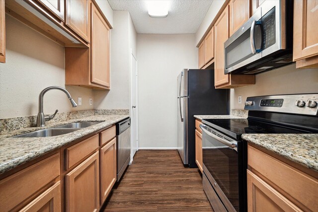 kitchen with stainless steel appliances, dark hardwood / wood-style flooring, sink, light stone counters, and a textured ceiling