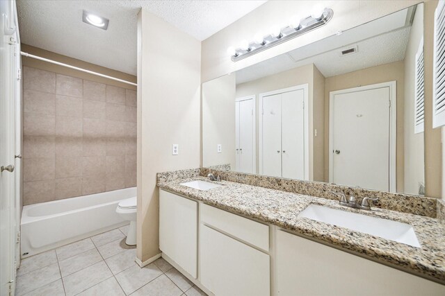 full bathroom featuring tile patterned flooring, a textured ceiling, double vanity, tiled shower / bath, and toilet