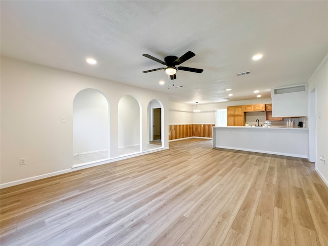 unfurnished living room with a textured ceiling, sink, ceiling fan, and light hardwood / wood-style floors