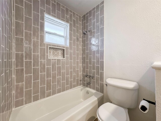 bathroom featuring toilet and tiled shower / bath combo