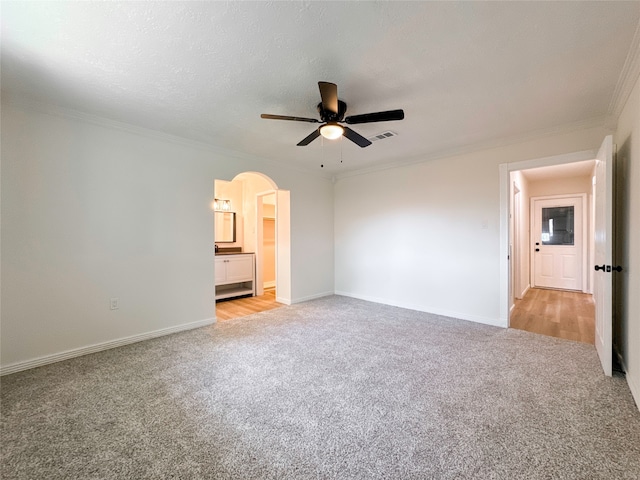 unfurnished bedroom with a textured ceiling, light hardwood / wood-style floors, crown molding, connected bathroom, and ceiling fan