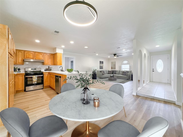 dining area featuring a textured ceiling, ceiling fan, sink, and light hardwood / wood-style floors