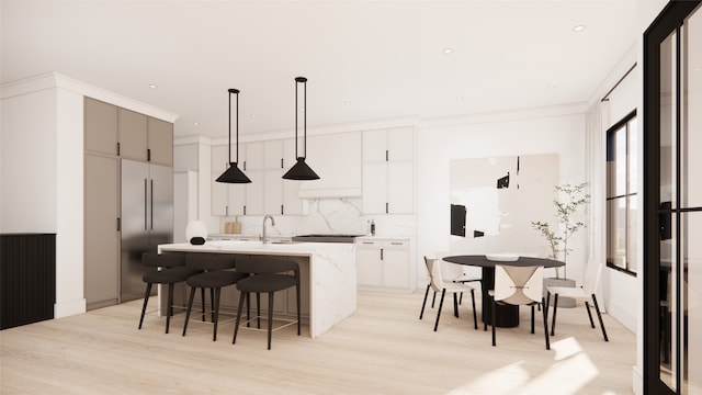 kitchen featuring a breakfast bar area, light hardwood / wood-style flooring, hanging light fixtures, and an island with sink