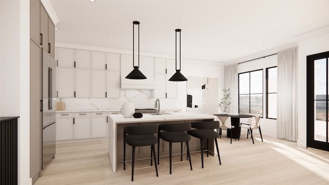 kitchen featuring light wood-type flooring, high end fridge, an island with sink, decorative backsplash, and pendant lighting