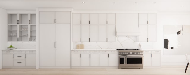 kitchen featuring range with two ovens, light hardwood / wood-style flooring, white cabinets, premium range hood, and decorative backsplash