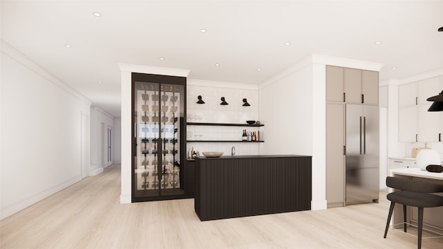 bar with stainless steel built in fridge, white cabinetry, light wood-type flooring, and ornamental molding