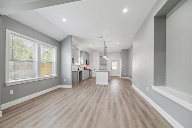 unfurnished living room featuring light wood-type flooring, a chandelier, and sink