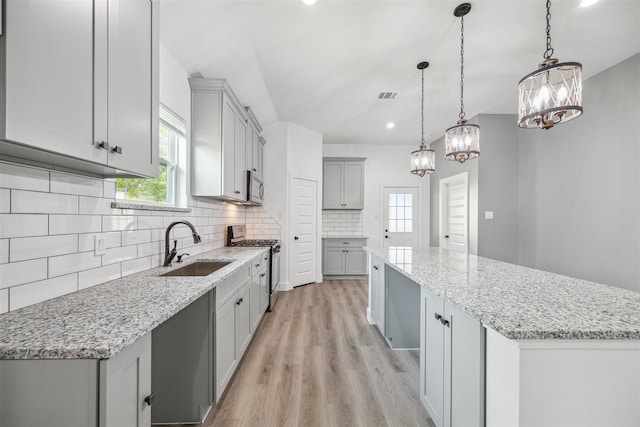 kitchen featuring pendant lighting, sink, a kitchen island, light hardwood / wood-style flooring, and stainless steel appliances