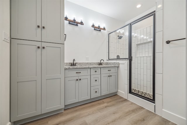 bathroom featuring wood-type flooring, a shower with door, and vanity