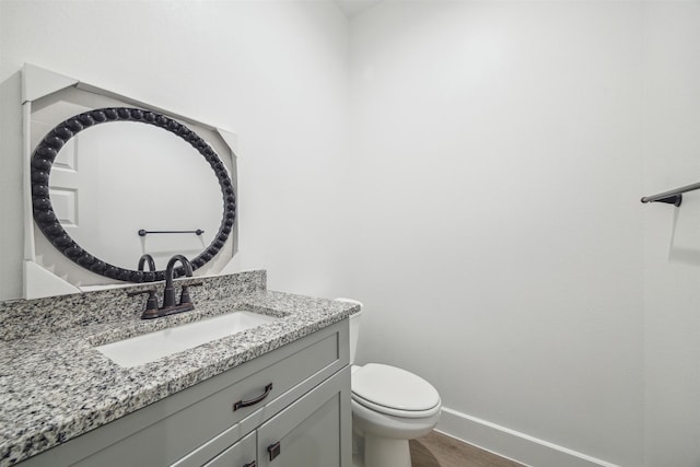 bathroom with vanity, toilet, and hardwood / wood-style flooring