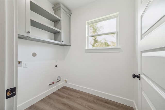 clothes washing area with gas dryer hookup, light wood-type flooring, hookup for an electric dryer, and cabinets