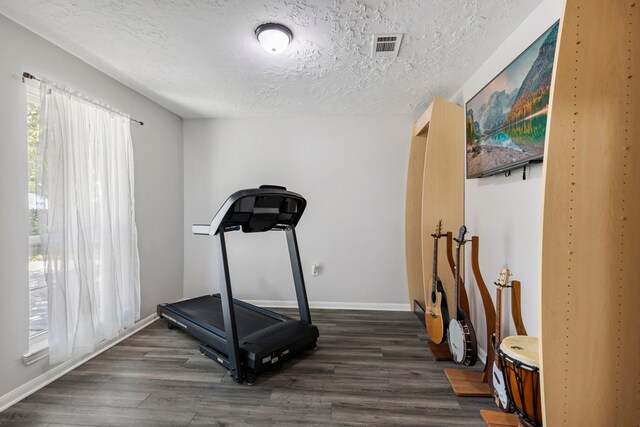 workout area with dark hardwood / wood-style flooring and a textured ceiling