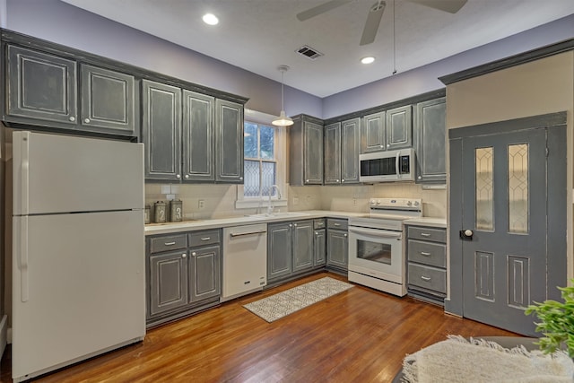 kitchen with tasteful backsplash, white appliances, ceiling fan, gray cabinets, and dark hardwood / wood-style floors