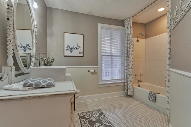 bathroom with tile patterned flooring, tiled shower / bath combo, vanity, and a textured ceiling