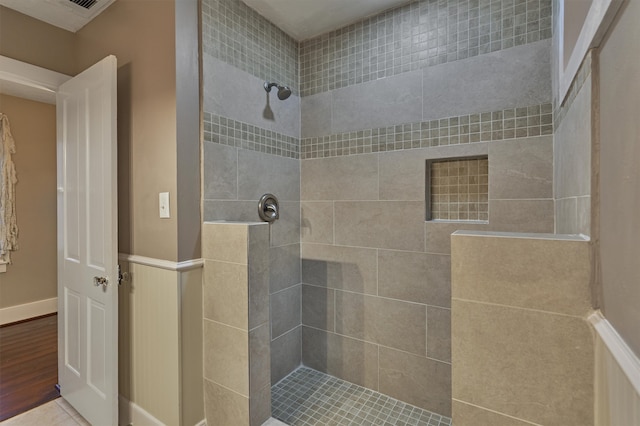 bathroom with a tile shower and hardwood / wood-style flooring