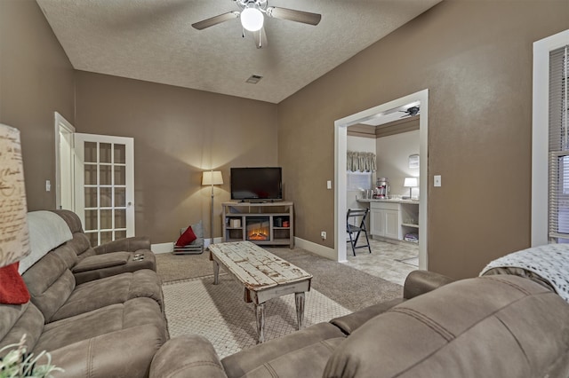 carpeted living room with a textured ceiling, a fireplace, and ceiling fan