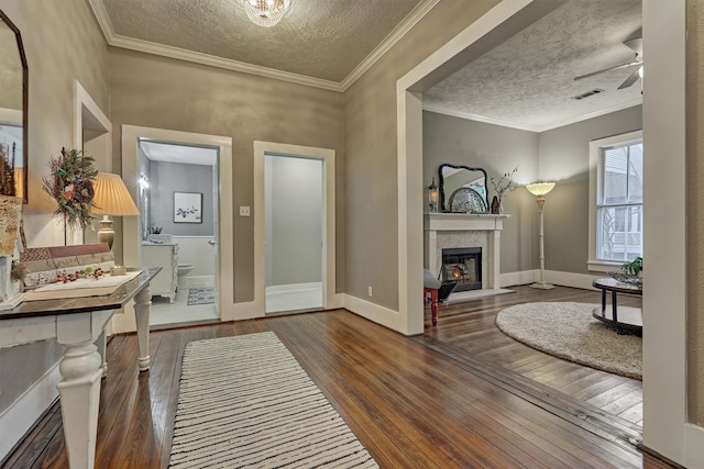 foyer entrance featuring dark hardwood / wood-style flooring, a textured ceiling, ceiling fan, and crown molding