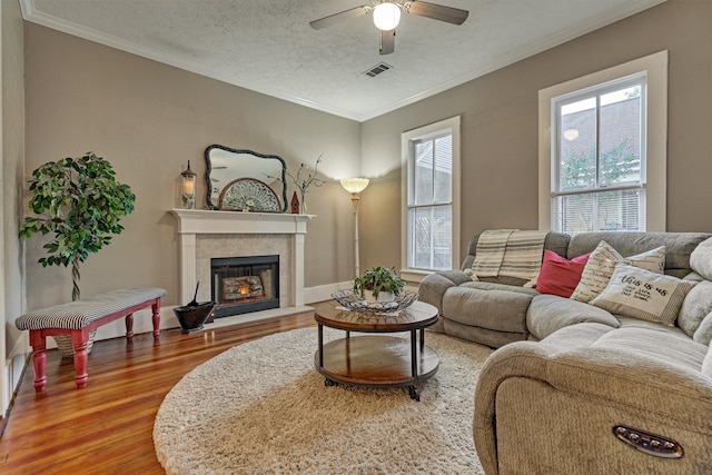 living room with a textured ceiling, ceiling fan, wood-type flooring, and ornamental molding