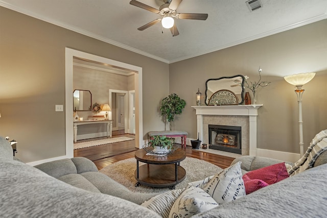 living room featuring crown molding, a tile fireplace, hardwood / wood-style floors, and ceiling fan