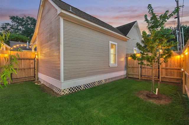 property exterior at dusk featuring a yard