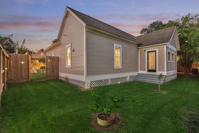 property exterior at dusk featuring a yard