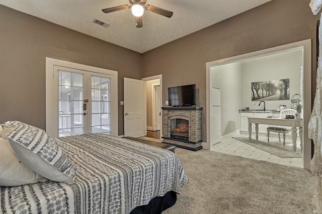 bedroom with a fireplace, ceiling fan, light carpet, french doors, and access to exterior