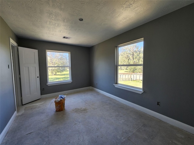 empty room with plenty of natural light and a textured ceiling