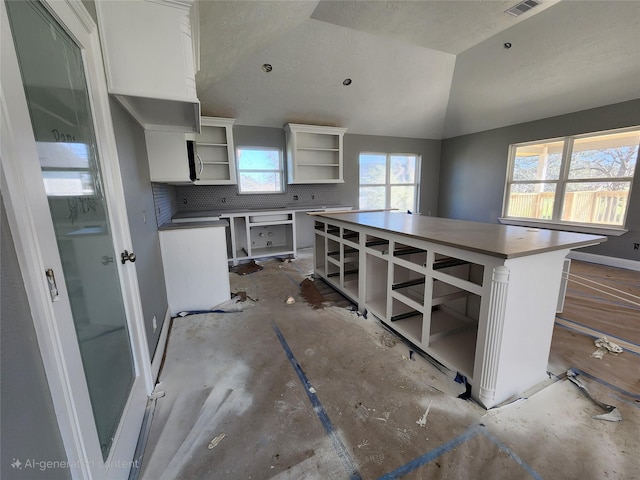 kitchen with white cabinetry, a center island, a healthy amount of sunlight, and open shelves