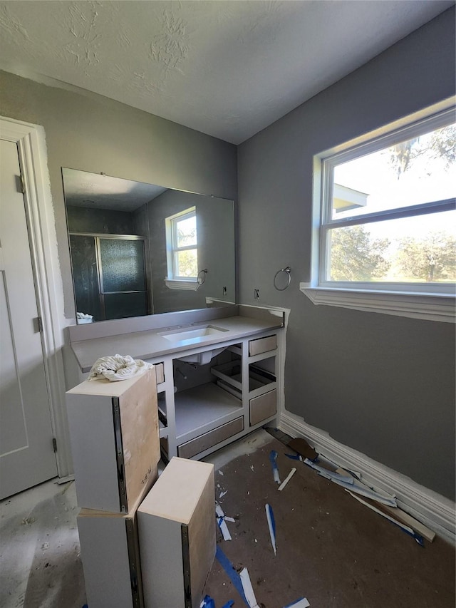 full bathroom with a shower stall, baseboards, and vanity