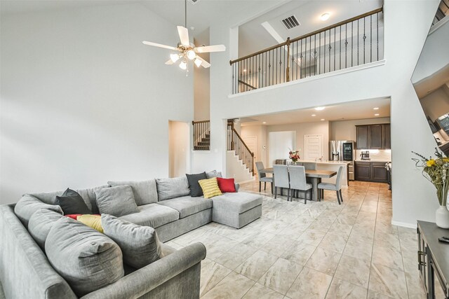 living room featuring light tile patterned flooring, ceiling fan, and a high ceiling