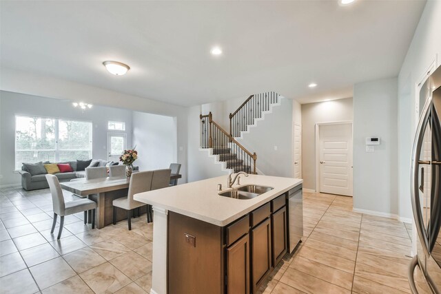 kitchen with appliances with stainless steel finishes, sink, a kitchen island with sink, and light tile patterned floors