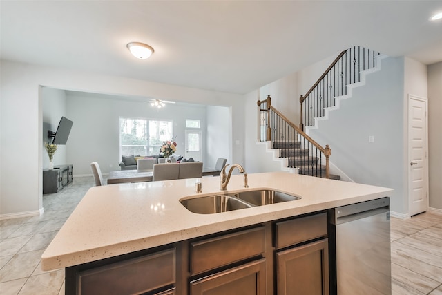 kitchen with light tile patterned flooring, dishwasher, light stone counters, an island with sink, and sink