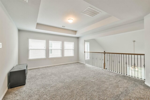 carpeted spare room with a raised ceiling